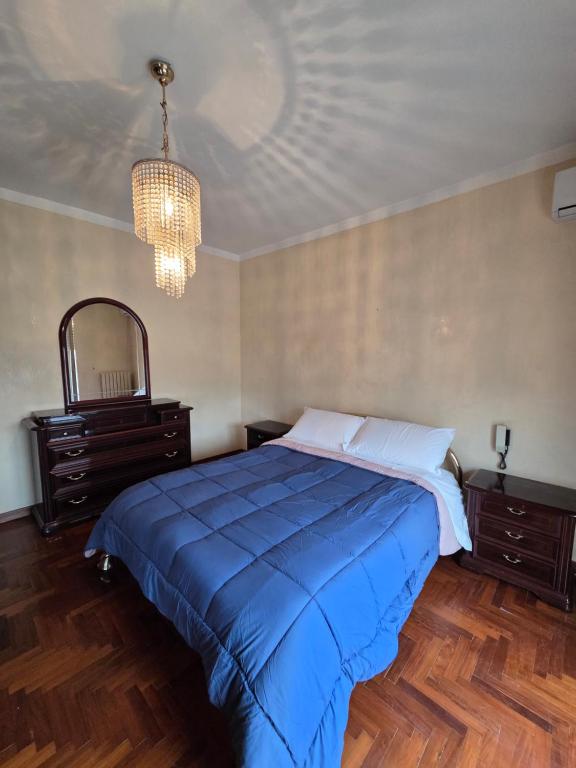a bedroom with a large blue bed and a chandelier at Appartamento Polidea in Reggio di Calabria