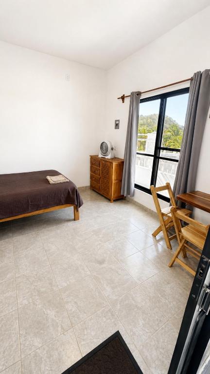 a bedroom with a bed and a table and a window at Casa Arena, Zipolite Playa del Amor in Zipolite