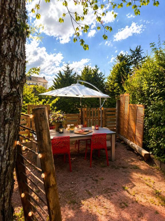 a table and chairs under an umbrella in a yard at Chez Kapameï in La Clayette