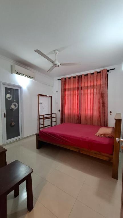 a bedroom with a red bed with a red curtain at Joyous Cottage in Maharagama