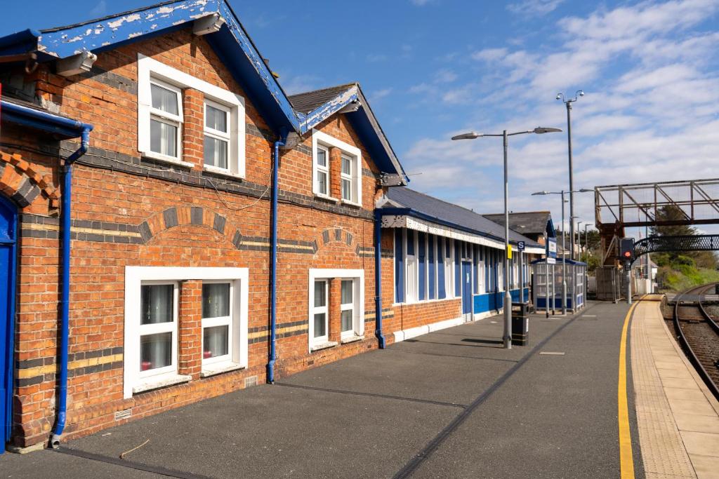 a brick building with white windows on a train station at Railway Sleeper Hostel in Castlerock