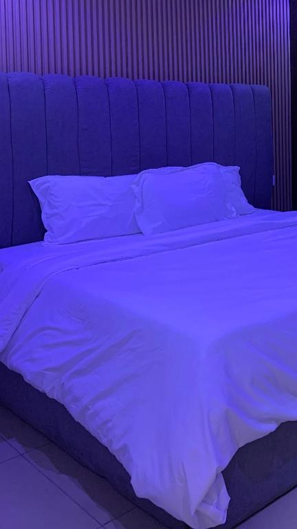 a blue bed with white sheets and pillows at Kris Courts in Ibadan