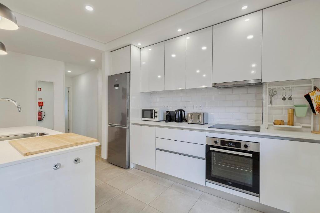 a white kitchen with white cabinets and appliances at Fonte Nova Nest, By Home Match in Setúbal
