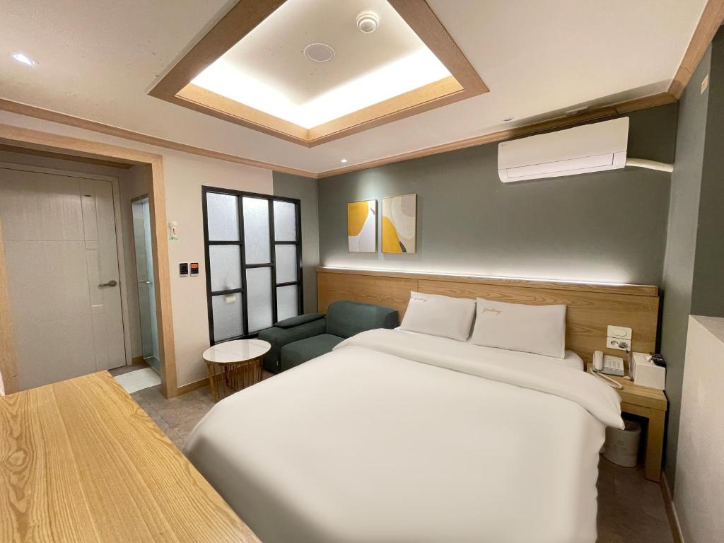 a bedroom with a large white bed and a couch at Gallery Motel in Seongnam