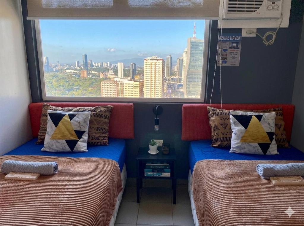 two beds in a room with a large window at Isaiah CityScape in Manila