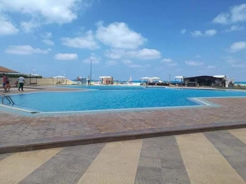a large blue swimming pool with a blue sky at Chatet on Casabinca NorthCoast in Dawwār Abū Maḩrūs