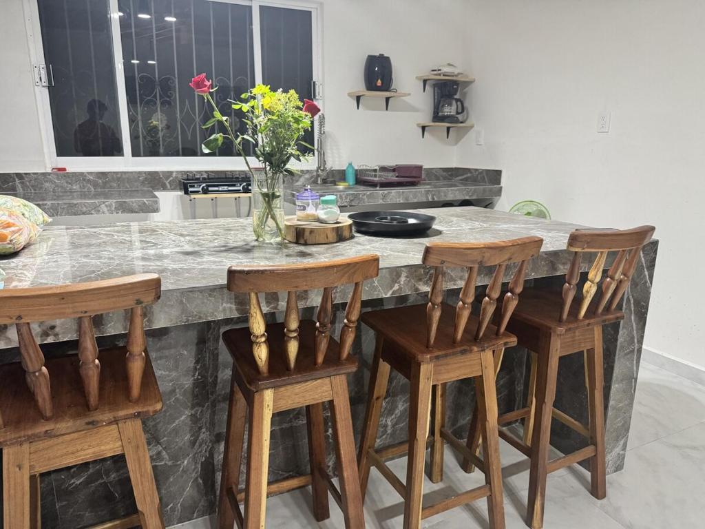 a kitchen with a counter with four wooden bar stools at Aldea Cardumen in Isla Aguada