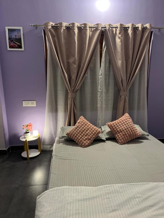 a bedroom with a bed with a curtain and two pillows at inoru house in Siliguri