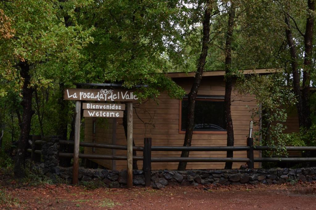 a sign in front of a building with a house at Cabañas La posada del Valle in Las Trancas