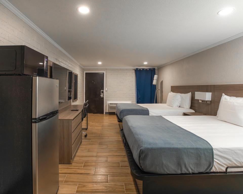 a hotel room with three beds and a refrigerator at Economy Suites Springfield - Extended Stay in Springfield