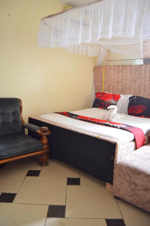 a bedroom with two beds and a chair at Kanaprime Hotels & Safaris Shanzu pride in Mombasa