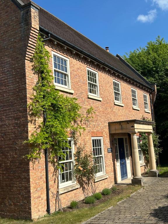 an old brick building with a tree in front of it at Bourne House in Mursley