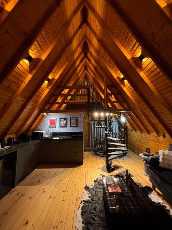 an attic room with a wooden ceiling and a kitchen at Chalé Recanto da Ema in Urubici