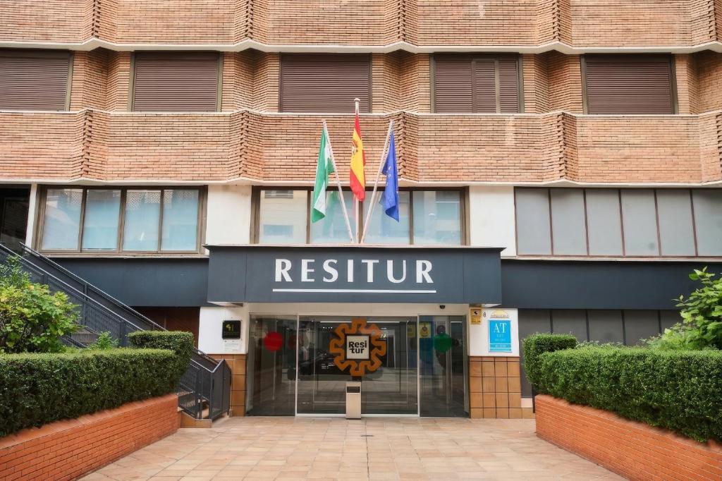 a hotel with three flags in front of a building at Apartamentos Resitur in Seville