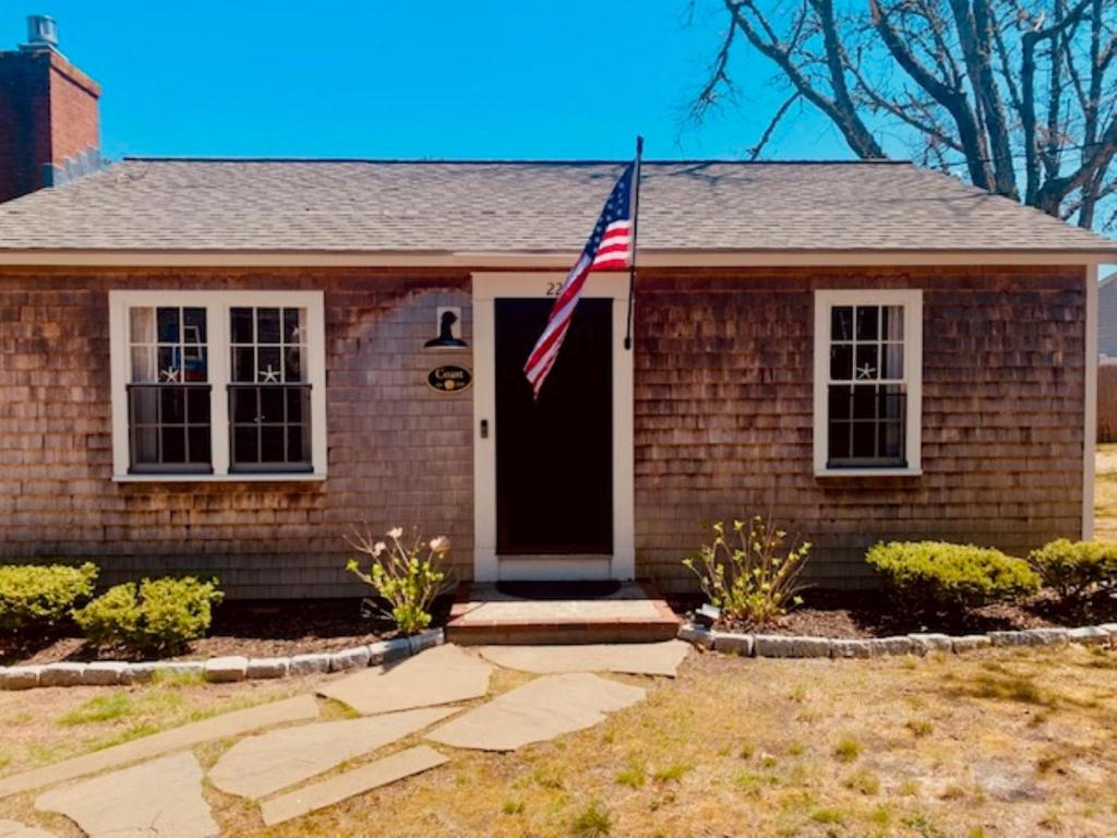 a house with an american flag in front of it at The Coast: Cozy Cape Escape in Dennis Port in Dennis Port