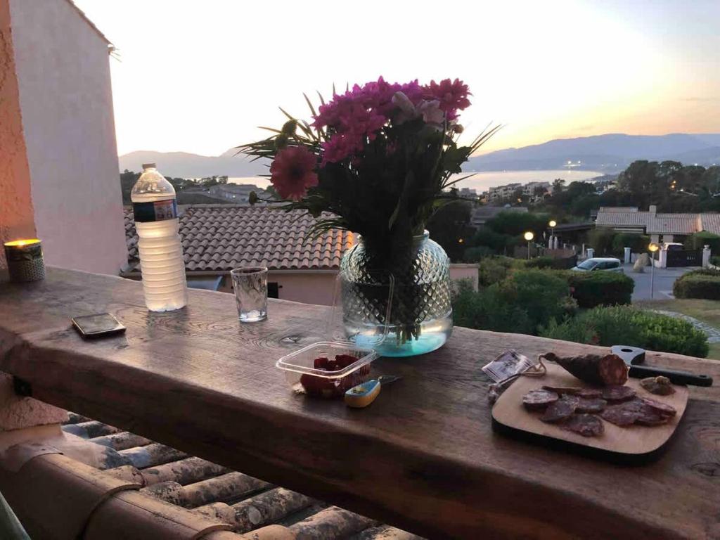 a table with a vase of flowers and a plate of food at Casamea - T2, Piscine, Vue Mer, Clim, Balcon in Porticcio