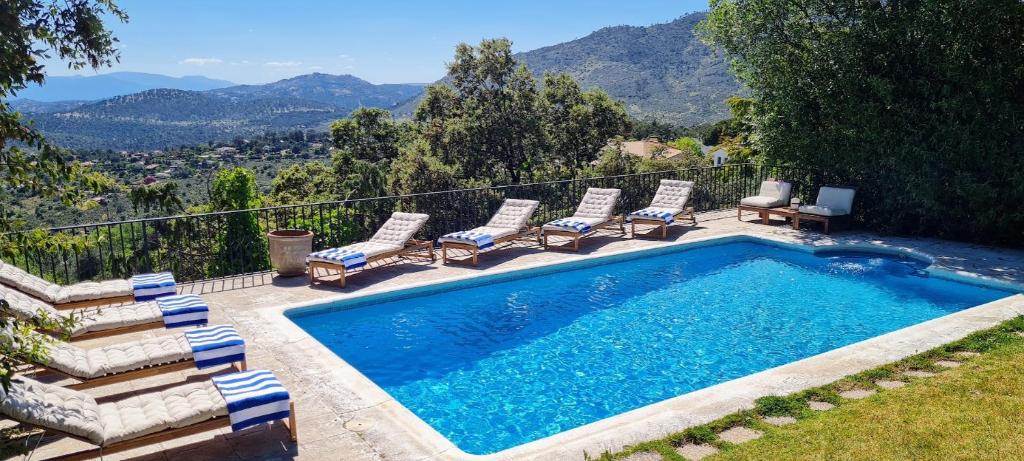 a swimming pool with chairs and a view of mountains at Casa Las Picoteras in La Estación
