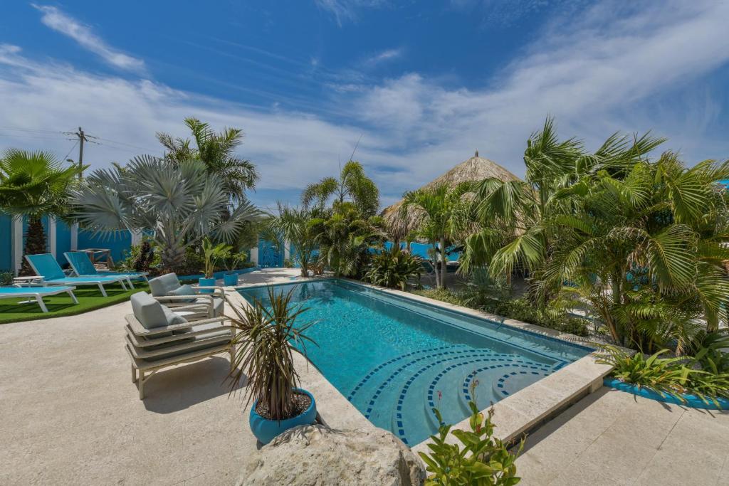 a swimming pool in a resort with palm trees at Atupa House in Noord