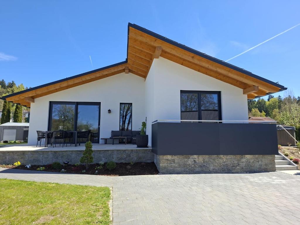 a small white house with a wooden roof at Mein Haus am See in Waldkirchen