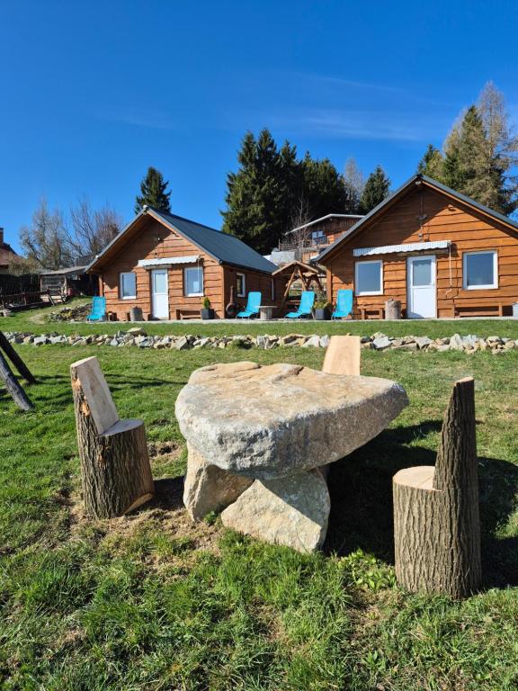 a stone bench sitting in the grass in front of a cabin at Sunset Holidays - Boska Nora in Komarno