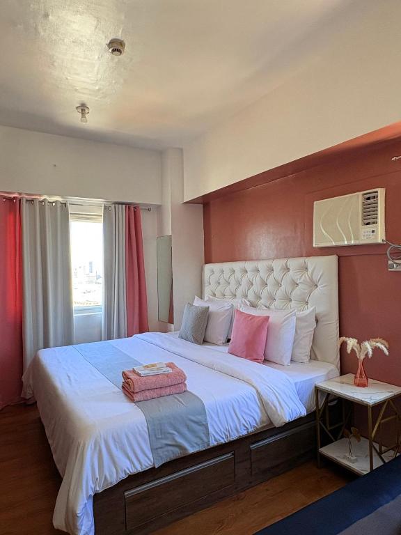 a bedroom with a large bed with pink and white pillows at Sunvida Tower Corner Suite Across SM Cebu in Cebu City