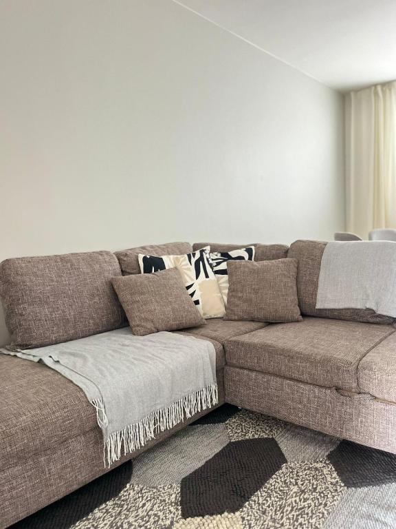 a brown couch with pillows in a living room at Seminaari Hill Suite in Jyväskylä