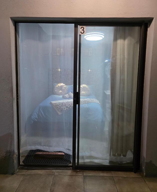 a glass door with a bed in a room at Mgwenya Capsule Hotel in Nelspruit