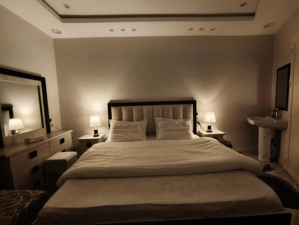 a bedroom with a large bed and a sink at شقق ضوء القمر Moonlight Apartment in Rahwat al Barr