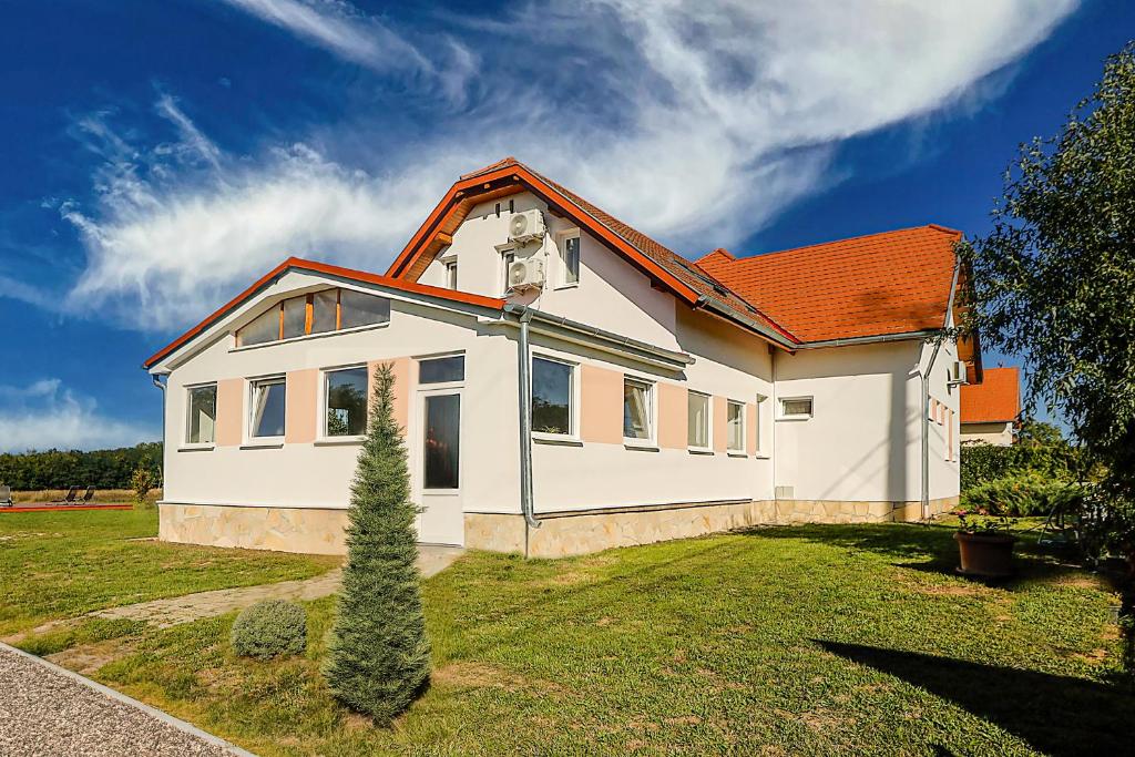 a white house with a tree in the yard at Anna Vendégház Szeleste in Szeleste