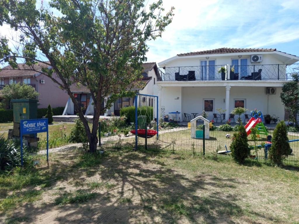 a white house with a tree and a playground at Sobe Išić in Veliko Gradište