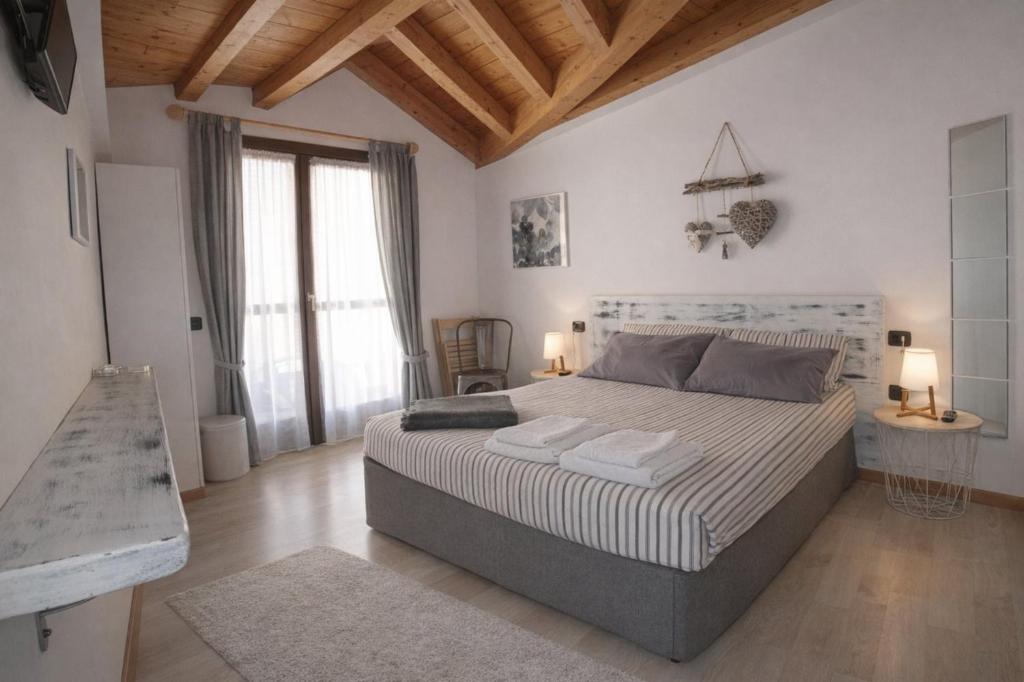 a bedroom with a large bed and a wooden ceiling at Albergo Garnì Casa del Lago in Tenno