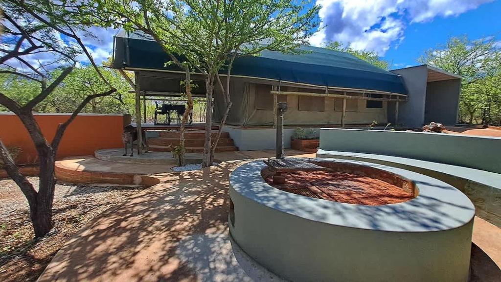 a garden with a fire pit in front of a building at Zuri Camp - Tent Kiama in Tsumeb