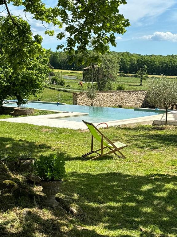 a chair sitting in the grass next to a swimming pool at 9 La Roche La Bergerie in Saint-Plantaire