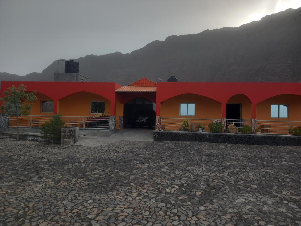 a red and orange building with a mountain in the background at Casa Pirinha in Portela