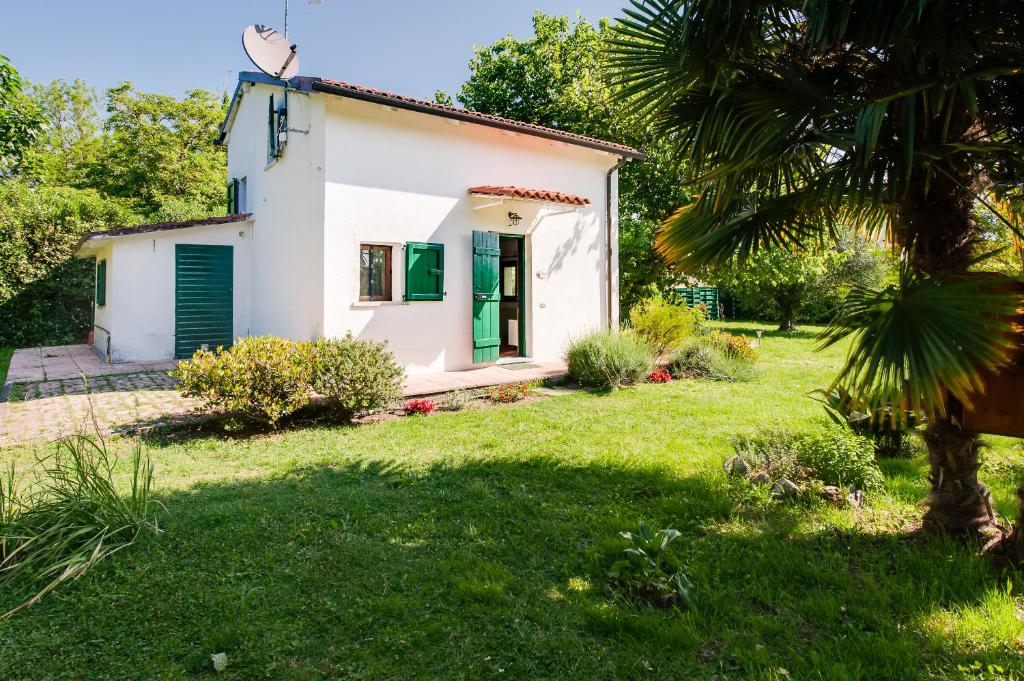 uma pequena casa branca com uma porta verde num quintal em Il Fienile em Ameglia