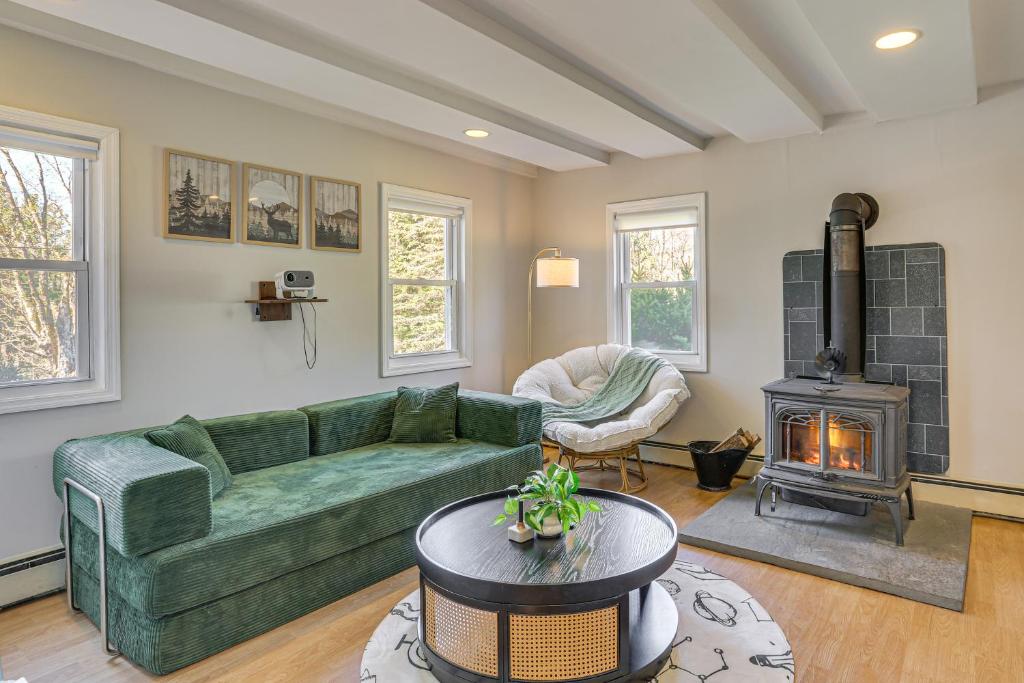 a living room with a green couch and a fireplace at Tranquil Catskills Home w/ Creek & Fire Pits in Parksville
