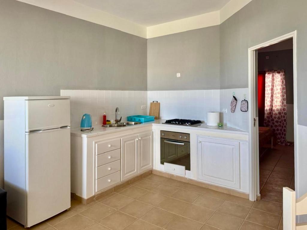 a kitchen with white cabinets and a white refrigerator at Ponta Preta Village 9 in Vila do Porto
