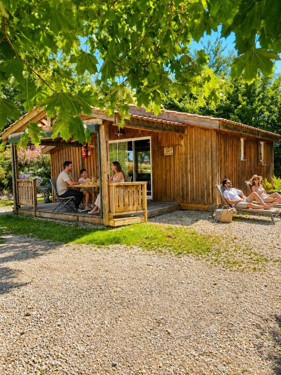 a group of people sitting outside of a cabin at Les Chalets du Brusquand in Marquay