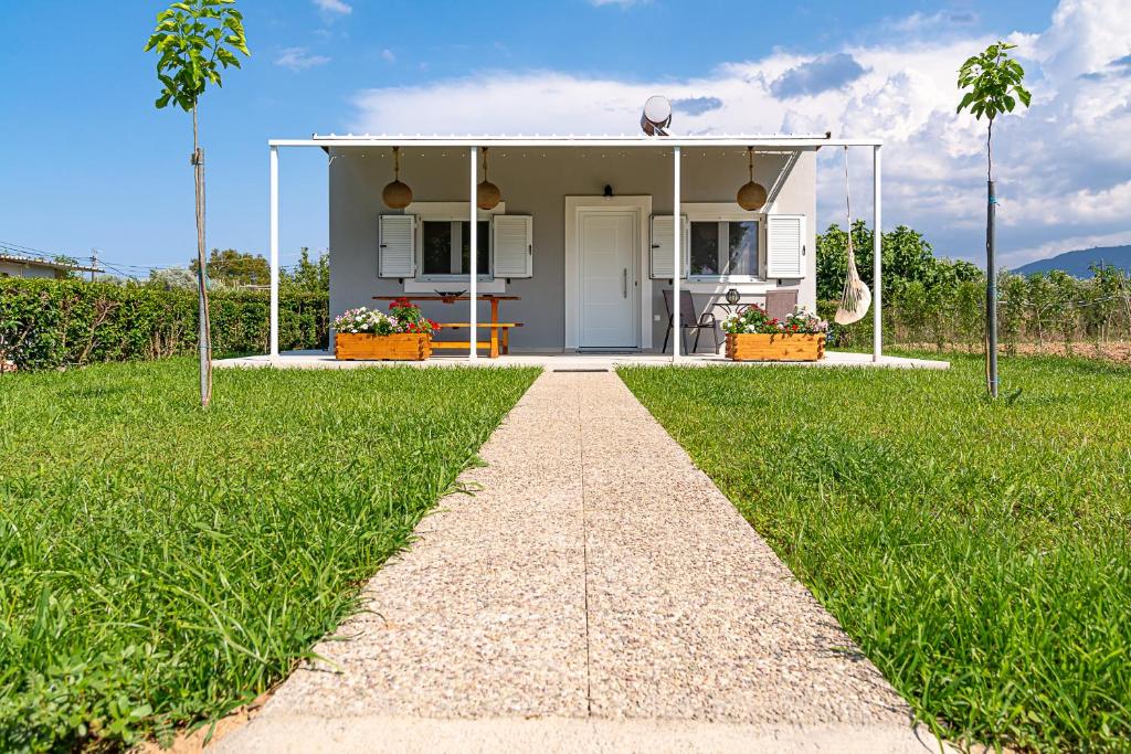 a small white house with a pathway in the grass at Μάζης Εξοχικές Κατοικίες in Dhiyeliótika