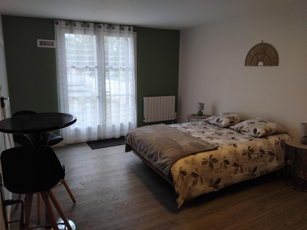 a bedroom with a bed and a table and a window at Chambre in Château-Garnier