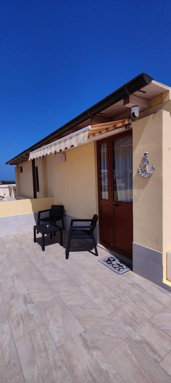 a building with a porch with two benches in front of it at Appartamenti Vincenzo Lampedusa in Lampedusa