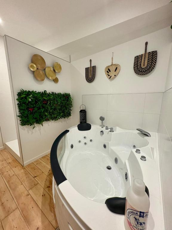 Eine weiße Badewanne in einem Badezimmer mit Pflanzen an der Wand in der Unterkunft Le Cocon Central avec Balnéo in Roanne
