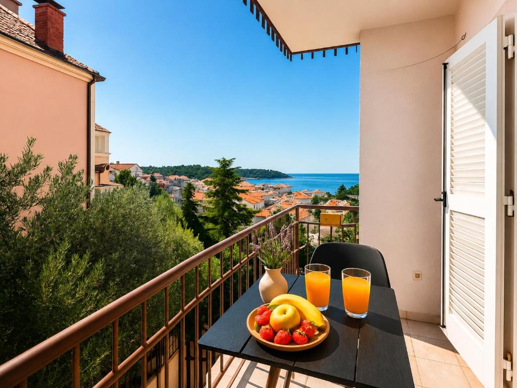 a table with a bowl of fruit and two glasses of orange juice at Apartman Ivanto in Makarska