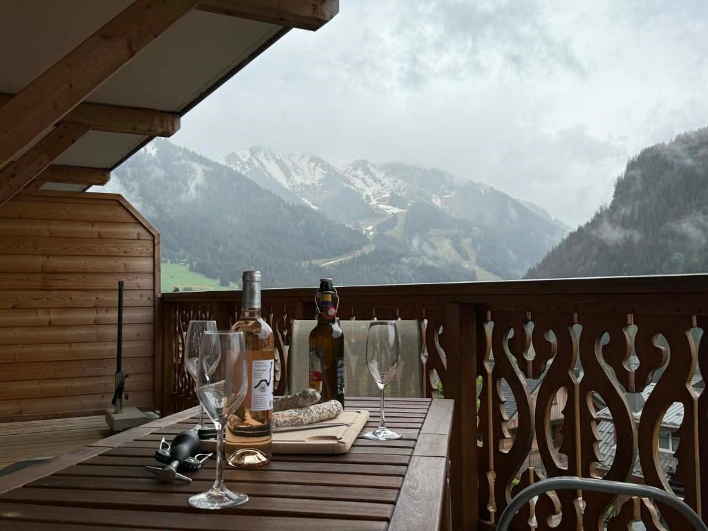 a table with wine bottles and glasses on a balcony at Perle de Savoie Free multipass offer for 4 guests in Châtel