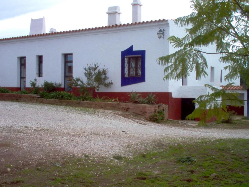 Casa blanca con ventana azul y patio en Herdade do Monte Outeiro - Turismo Rural, en Venda