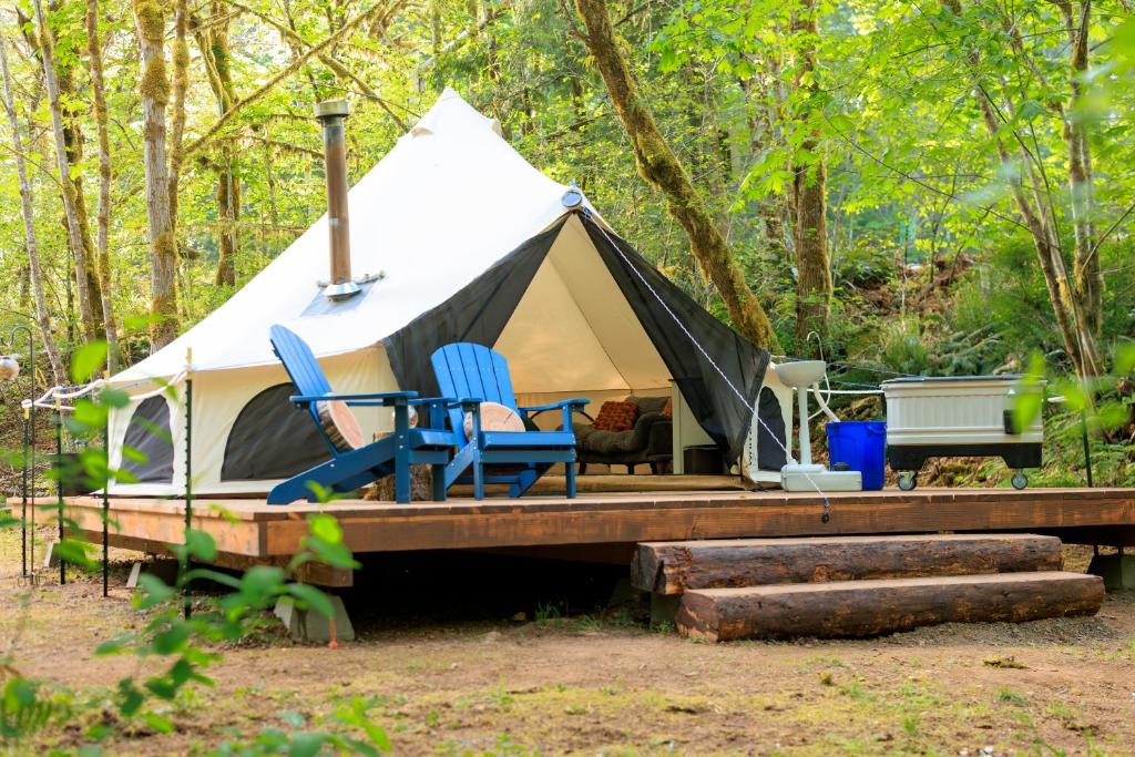 a tent with chairs on a wooden deck in the woods at Creekside Retreat at Triangle Lake in Blachly