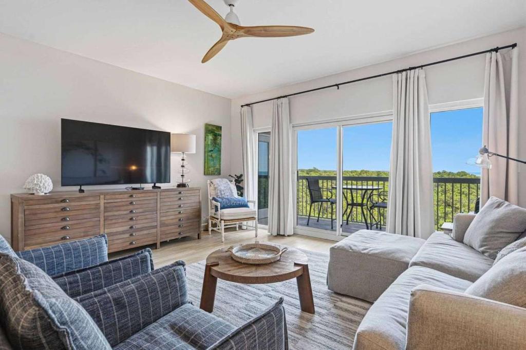 a living room with a couch and a tv at Easy Beach Walk Pools and Hot Tubs in Destin