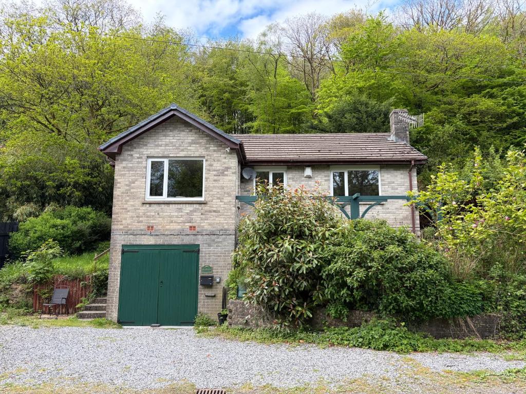a small brick house with a green garage at Glanafon in Abergorlech
