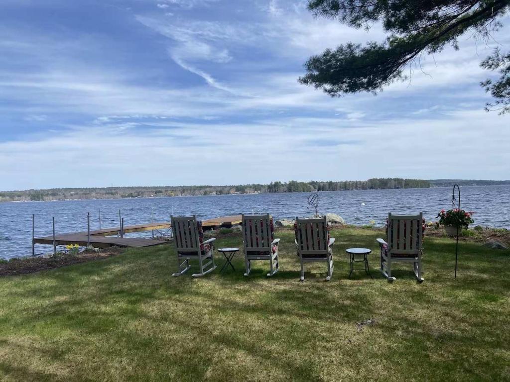 three chairs and a table in front of a lake at Sebago Waterfront Escape with Private Dock in Windham