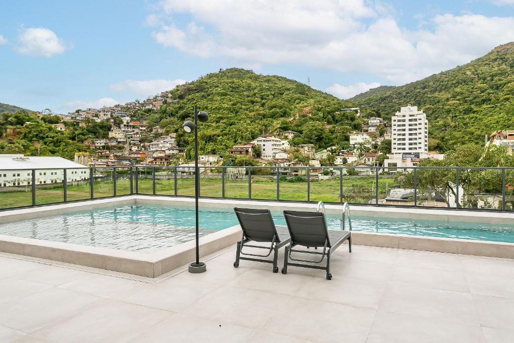 a couple of chairs sitting next to a swimming pool at Modern Studio | Pool | Gym #SG10 in Florianópolis
